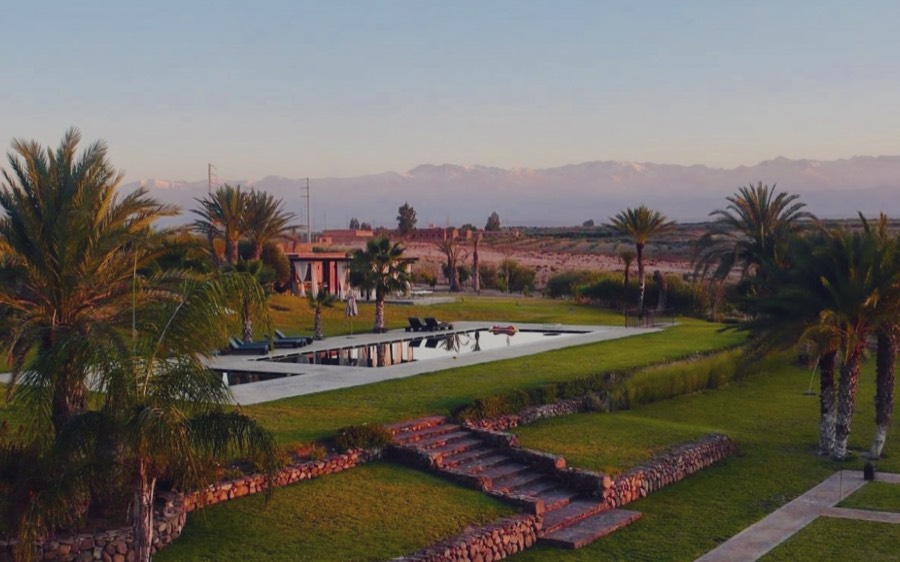 Le domaine de Tameslohte, près de Marrakech : palmiers et bassin face aux cimes enneigées de l’Atlas